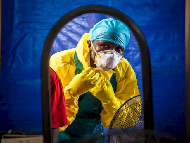 Ein Pfleger zieht sich in Sierra Leone Ebola-Schutzkleidung an