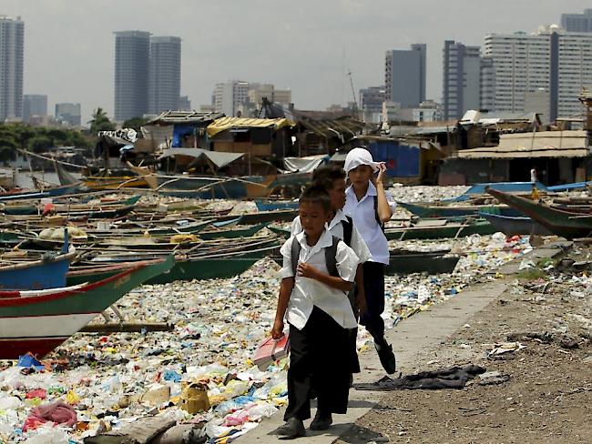 Schulkinder laufen in der philippinischen Hauptstadt Manila an einem mit Abfall verschmutzten Fluss entlang. Laut der IOM beschleunigt sich die globale Verstädterung rasant (Archiv)