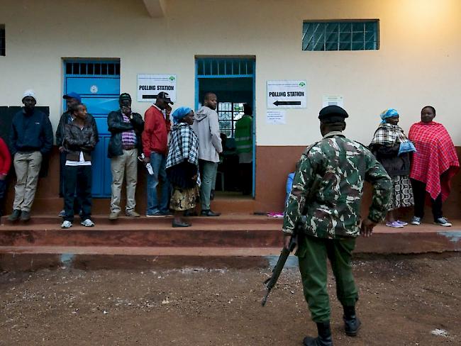 Unter den Augen einer Sicherheitskraft: Schlange vor einem Wahllokal in Kenias Hauptstadt Nairobi.