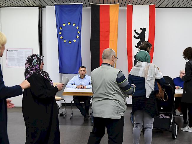 Wählerinnen und Wähler stehen in einem Wahllokal in Berlin an.