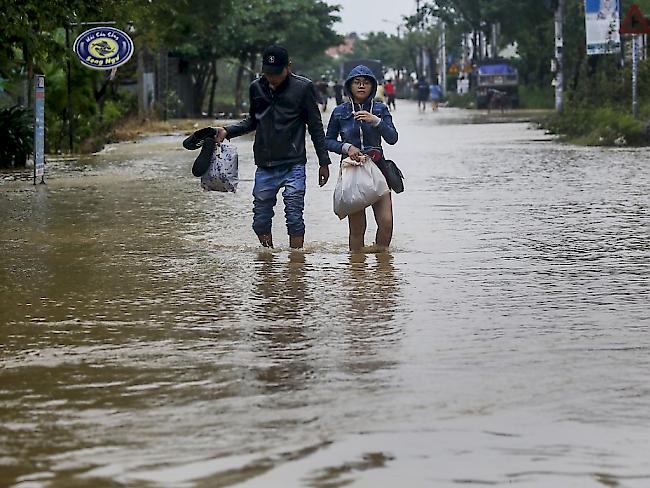 Ein Paar watet durch eine überflutete Strasse in Hoi An.