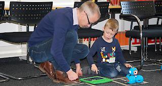 Vater und Sohn t&uuml;fteln an einem Parcour f&uuml;r Roboter &laquo;Dash&raquo;.