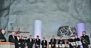 Grosse Stimmung. Oktett &laquo;Vocalisti&raquo; und Quartett &laquo;Brassiz Navidad&raquo; vor der durch Lichts&auml;ulen geheimnisvoll beleuchteten &laquo;H&ouml;hlenwand&raquo; der Felsenkirche Raron.  