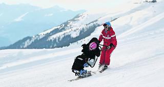 Grenzen erweitern. Oben: Ein M&auml;dchen geniesst die Pistenabfahrt sichtlich. Unten links: Der Dualski kann ausgeklappt werden, sodass er sich auch f&uuml;r Sessellifte eignet. Unten rechts: Vater Simon (rechts) fixiert mit Bruno Burgener Sohn Juli im Dualski. 