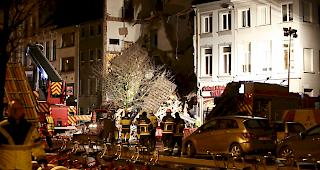 Feuerwehrleute inspizieren die Tr&uuml;mmer.