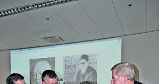 Diskussionsszene. Dr. Jakob Knaus (Zweiter von rechts) in einem kl&auml;renden Nachgespr&auml;ch mit interessierten Zuh&ouml;rern seiner Vortr&auml;ge. Im Hintergrund: Richard Strauss (links) und Dmitri Schostakowitsch anno 1935. 