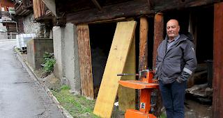 Michael Meyer vor seinem Stadel in Kippel. Neben ihm die Spaltmaschine.