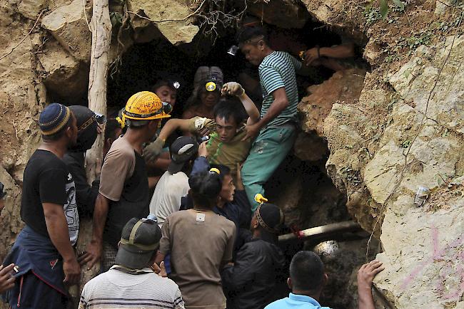 Retter tragen einen Überlebenden aus einer eingestürzten Mine in Bolaang. Durch den Zusammenbruch einer nicht lizenzierten Goldmine in Indonesien wurden Dutzende von Menschen begraben. Retter gruben am Mittwoch mit blossen Händen und landwirtschaftlichen Werkzeugen nach Opfern.