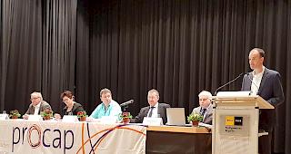 Der Vorstand von Procap: Heinrich Zengaffinen (v. links), Pia Schwery, Georges Locher, Valentin Pfammatter und Gesch&auml;ftsf&uuml;hrer Christophe M&uuml;ller. Am Rednerpult: Christian Escher, Gesch&auml;ftsf&uuml;hrer Atelier Manus. 
