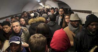 Pendler warten in Paris an einem Bahnsteig auf eine U-Bahn.