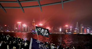 Hongkong: Protestierende singen, w&auml;hrend Feuerwerksk&ouml;rper entlang der Uferpromenade in Tsim Sha Tsui explodieren.