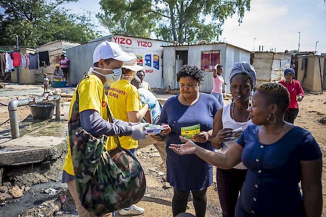 Ein Freiwilliger einer COVID-19-Aktionsgruppe verteilt Informationsbroschüren und Seife an Einwohner der Gemeinde Diepsloot in Johannesburg, Südafrika.