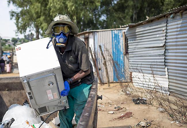Ein Arbeitsloser trägt eine Maske und eine Schutzbrille, als er in der Gemeinde Diepsloot in Johannesburg, Südafrika, Müll für den Wiederverkauf sammelt.