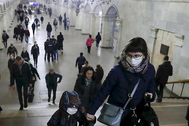 Eine Frau und ihr Kind tragen Schutzmasken, während sie die U-Bahn-Station Komsomolskaya in Moskau passieren.