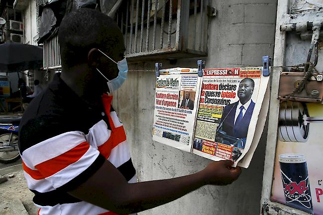 Nachrichtenüberblick: In der Millionenmetropole Abidjan in der Elfenbeinküste haben Einwohner ein Zentrum für Coronavirus-Tests zerstört. Dies geschah, weil sie ihre Ansteckung durch Besucher der Einrichtung fürchteten. (Archivbild: Ein Mann mit Gesichtsmaske liest die Schlagzeilen in Abidjan)