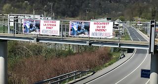 Eine Fussgängerüberführung und Warnplakate über einer leeren Landstrasse bei Avegno TI am Karfreitag.